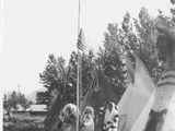 Black and white photo of a group of men in ceremonial dress raising the American flag, Saint Mary\