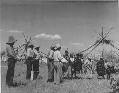 Black and white photo of a group of people erecting the lodge for the Pikuni tribe Sun Lodge Ceremonies, 1927