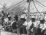 Black and white photo of a group of men sitting and playing drums, part of the Sun Lodge Ceremonies, Browning, Montana, 1927