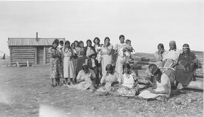 Black and white photo of a large group of women sitting and doing crafts.