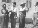 Black and white photo of Yellow Kidney, and others in front of a building with a couple more people in the background.