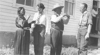 Black and white photo of Yellow Kidney, and others in front of a building with a couple more people in the background.