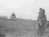 Black and white photo of Mrs. Little Dog with a child on her back, Alberta, Canada
