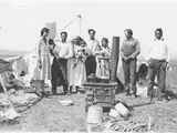 Black and white photo of a family standing in their encampment, Canada.