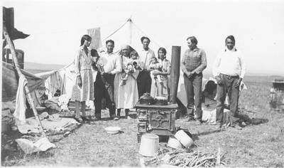 Black and white photo of a family standing in their encampment, Canada.