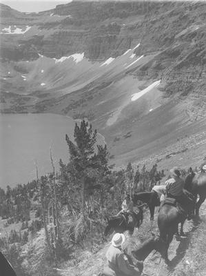 Black and white photo of a group of people on a trail ride, Upper Two Medicine Lake, Glacier National Park, Montana