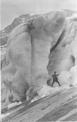 Black and white photo of a man standing next to an ice formation, Glacier National Park, Montana