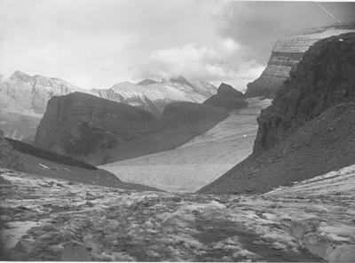 Black and white photo of an overlooking view of snow covered mountains in Glacier National Park