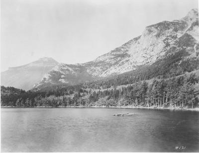 Black and white photo of a lake taken from the shore in Glacier National Park.