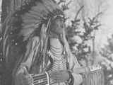 Photo of a side view of Eli Guardipee, Eli in Ceremonial Dress, holding a leather gun case