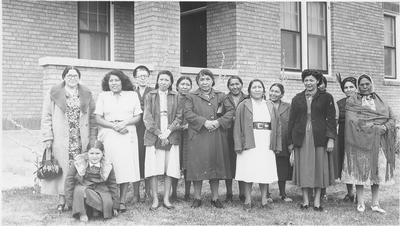 Photo of a group of women standing in front of a brick building