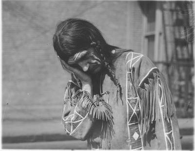 Indian Man in Traditional Buckskin Clothing Resting His Head in His Hand to Express Sleep Through Sign Language