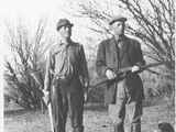 Two Men in Hunting Clothes Holding Guns