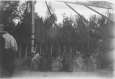 Large Group of Indian Men Wrapped in Blankets Huddled in a Circle During a Ceremony