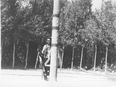 Photo of an Indian Man in Ceremonial Dress Dancing Around the Center Pole of a Lodge