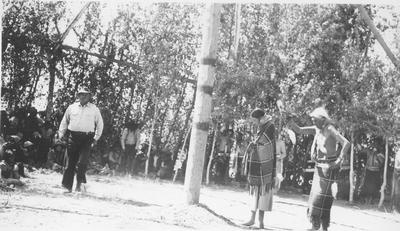 Man and Woman Stand in Front of Center Pole of the Lodge During a Ceremony