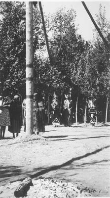 Large Group of Men and Women Standing in Front of the Center Pole During a Ceremony