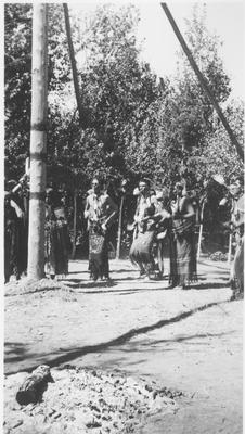 Group of Indian Men in Ceremonial Dress Dance in Front of a Center Pole During a Ceremony