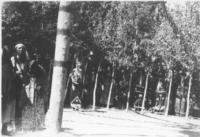 Photo of three people standing next to the center post, while the rest of the group stands along the tree line.