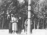 Photo of a small group of people standing around the center post of a lodge, during a ceremony