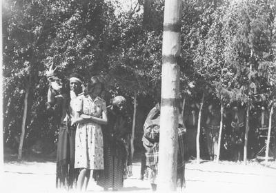 Photo of a small group of people standing around the center post of a lodge, during a ceremony