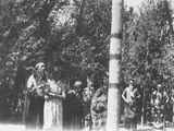 Photo of a group of people surrounding the center post of a ceremonial lodge